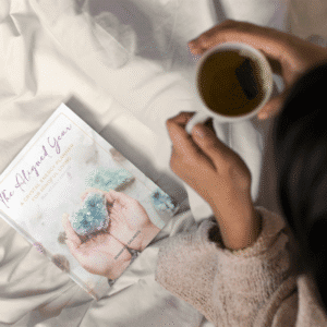 Cozy morning scene with The Aligned Year planner and cup of coffee on soft blanket.