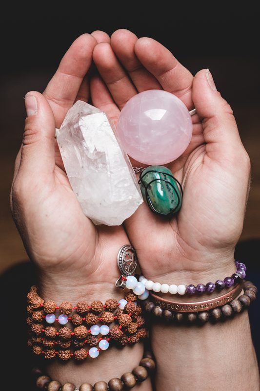 hands with crystals and gemstone bracelets on wrist