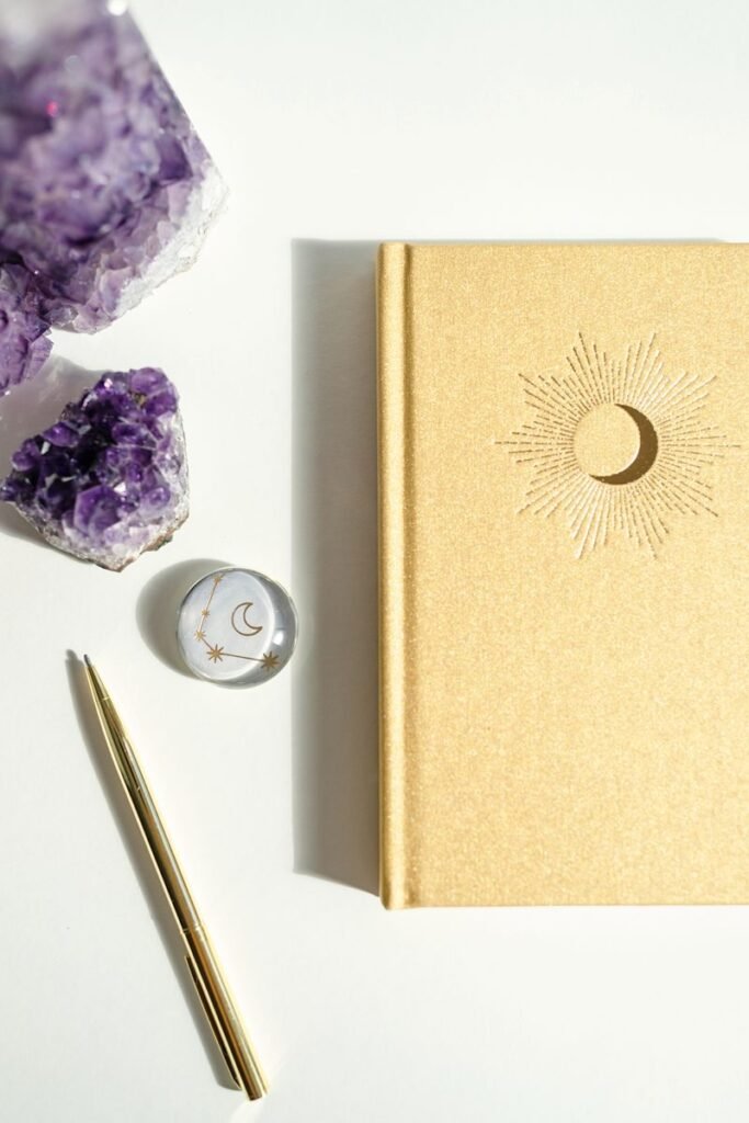 Gold journal on table with Amethyst cluster and pen